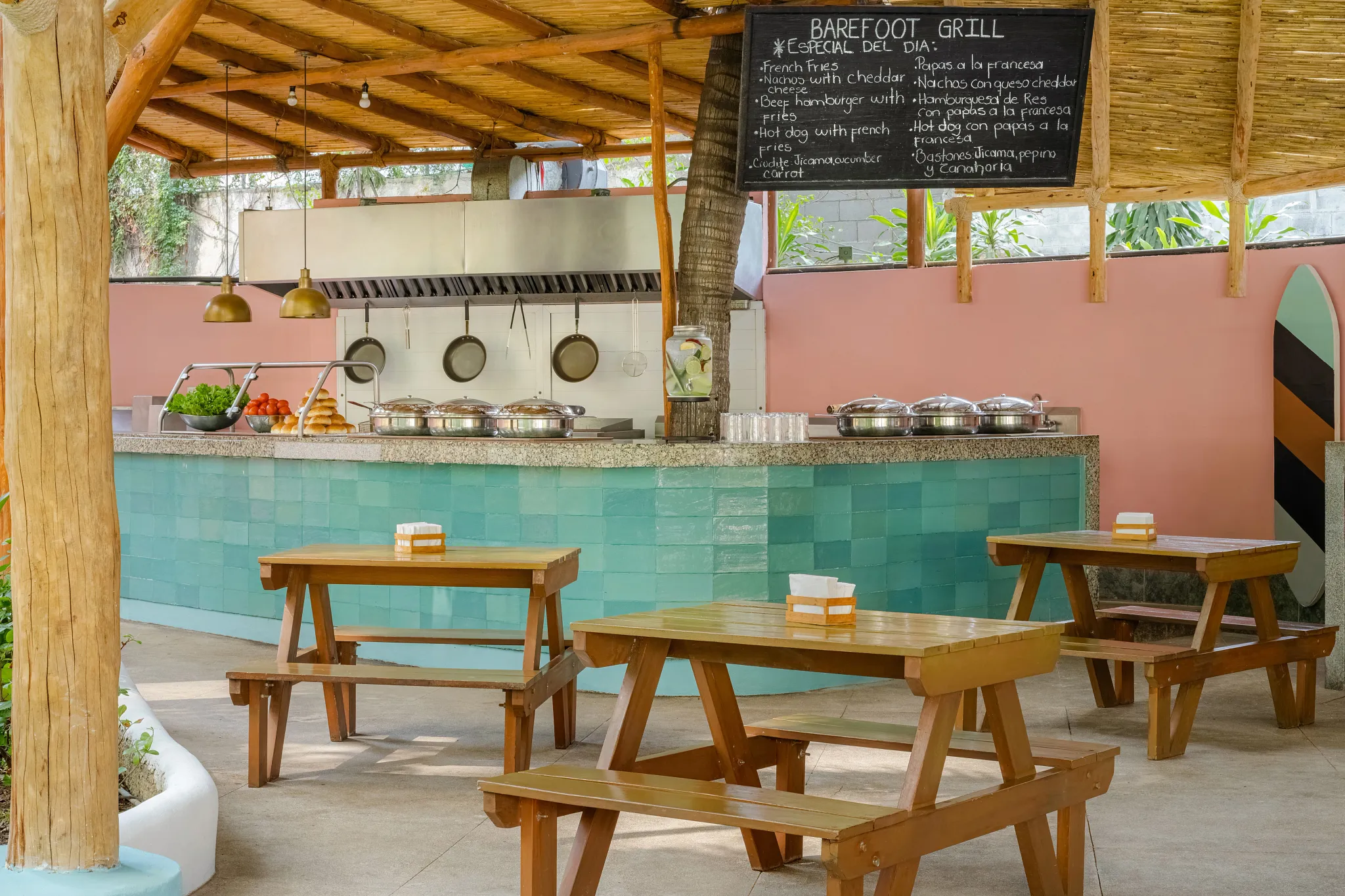 Barefoot Grill at Dreams Acapulco Resort & Spa featuring a casual poolside dining area with wooden picnic tables and an open-air grill station.