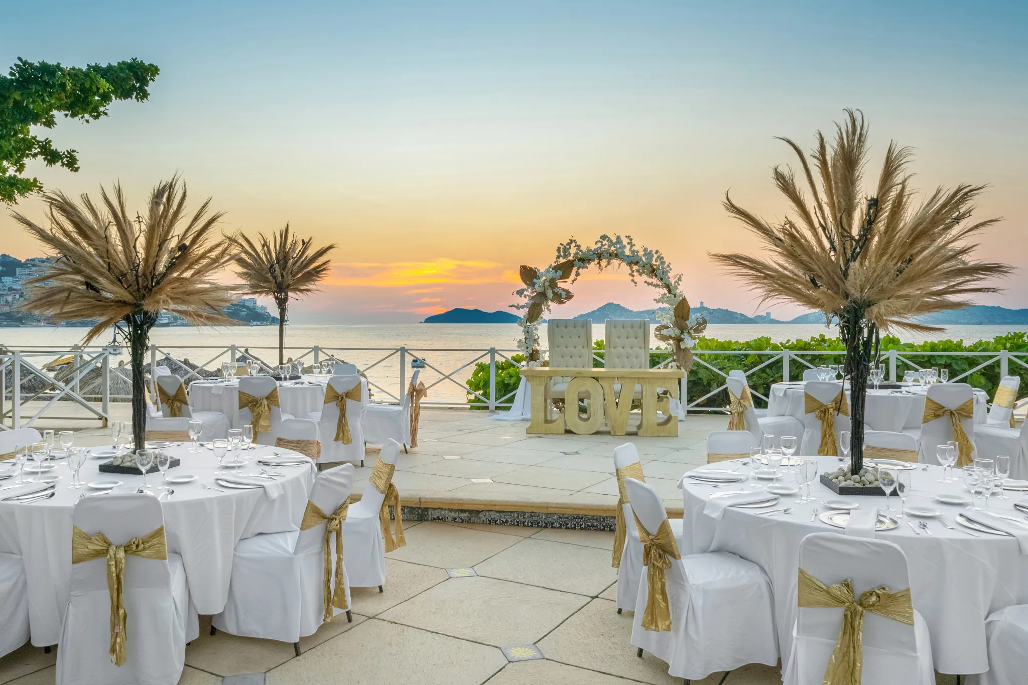 Oceanfront wedding reception setup with round tables at sunset at Dreams Acapulco Resort & Spa